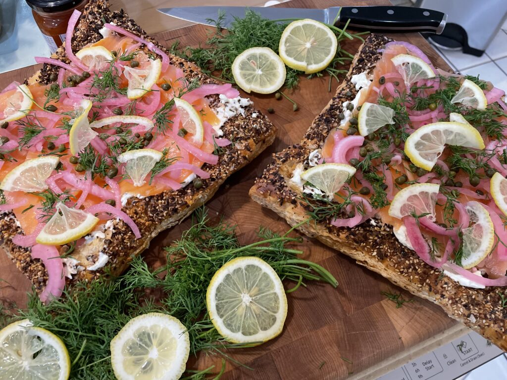 Smoked salmon tart displayed on a butcher block with lemon slices and dill